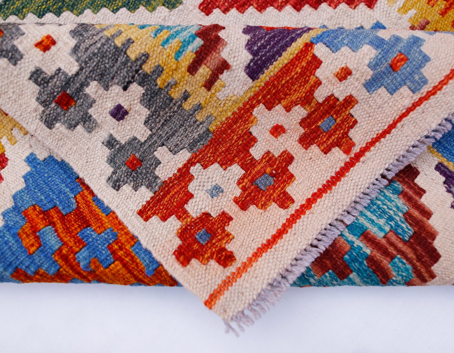 A handmade Afghan Maimana kilim runner featuring a colorful geometric pattern on wool.