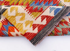 A folded Afghan Maimana Kilim runner featuring a vibrant geometric pattern in wool.