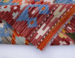 A handwoven Afghan Maimana kilim runner featuring a geometric pattern in vibrant wool colors.