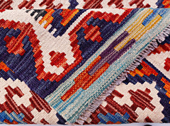 A handmade Afghan Maimana kilim runner featuring a geometric pattern in red, blue, and cream.