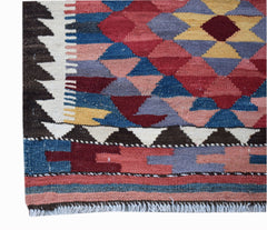 A handmade Afghan Maimana kilim runner featuring a geometric pattern in vibrant wool colors.