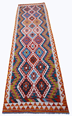 A handmade Afghan Maimana wool runner rug featuring a colorful geometric diamond pattern.
