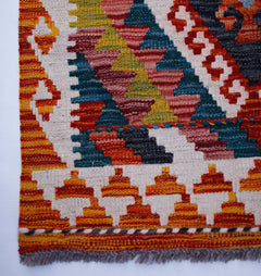 Handwoven Afghan Maimana wool runner featuring a vibrant geometric pattern in warm earth tones.