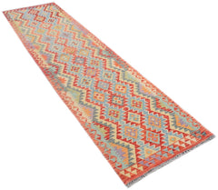 A handmade Afghan Maimana runner rug featuring a colorful geometric pattern on a wool flatweave.
