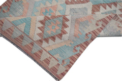 A handmade Afghan Maimana kilim runner featuring a geometric pattern in muted blue and pink tones.