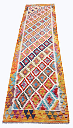A handmade Afghan Maimana wool runner rug featuring a colorful geometric diamond pattern.