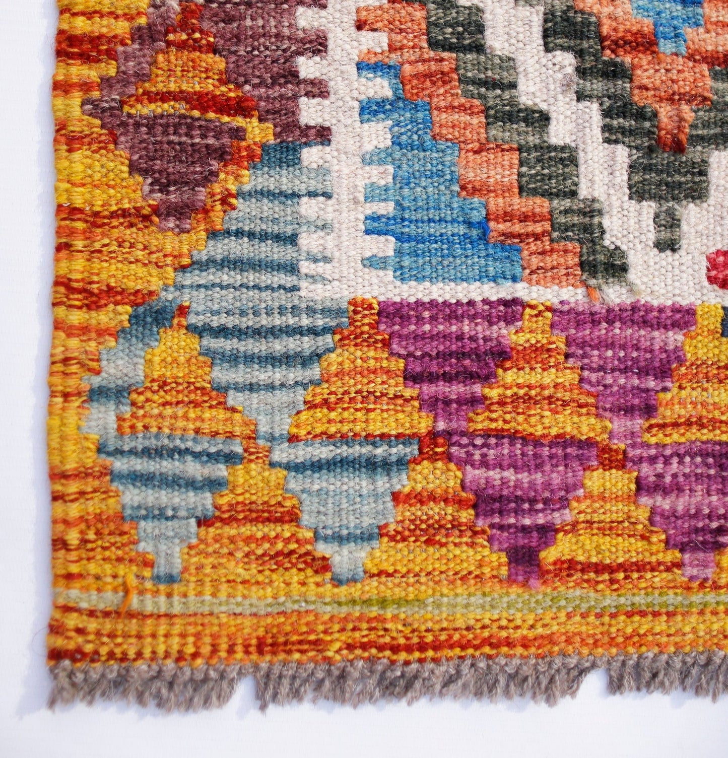 A handmade Afghan Maimana kilim runner featuring vibrant geometric patterns in wool.