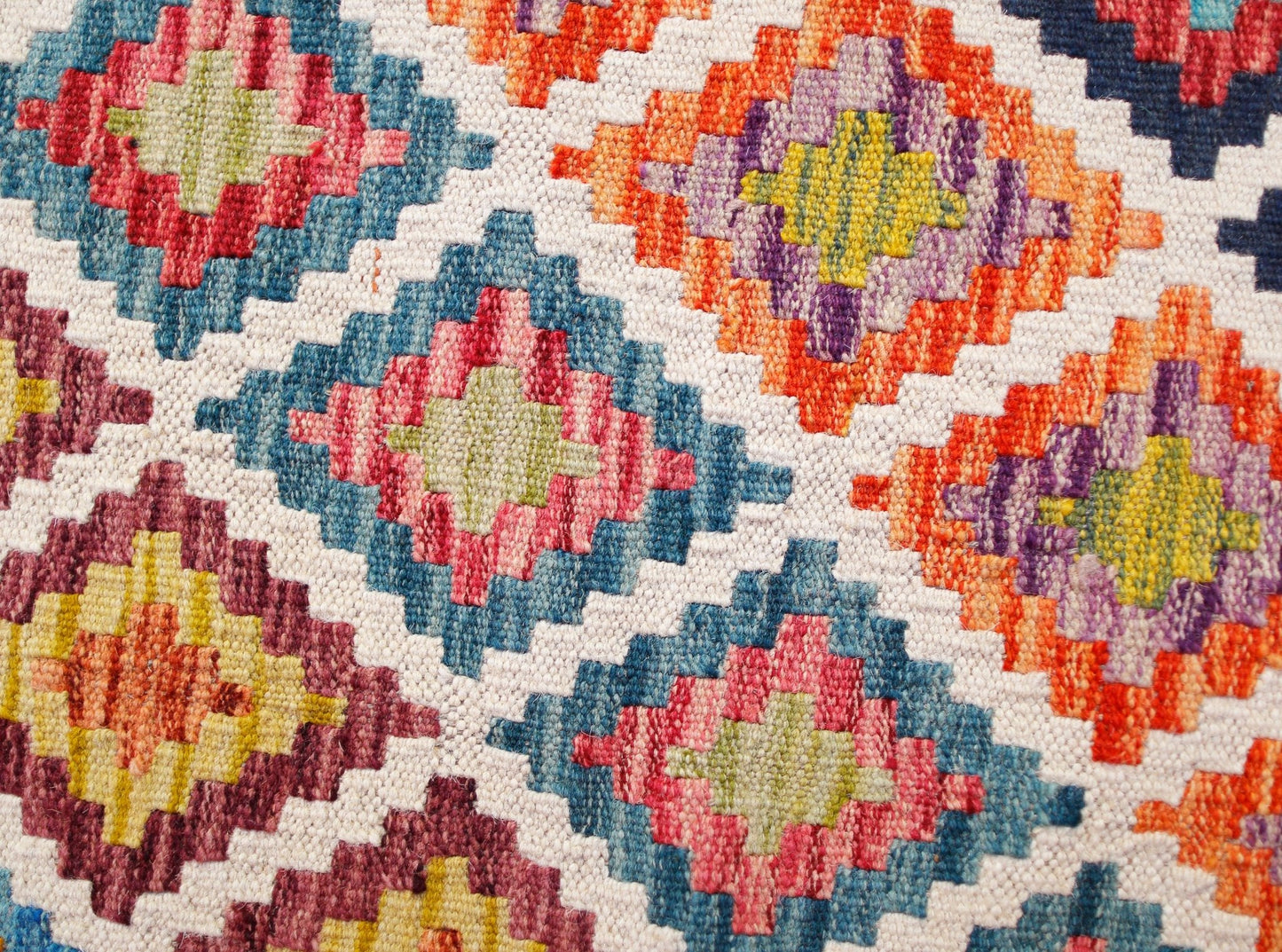 Handwoven wool kilim runner featuring a colorful geometric diamond pattern on a white background.