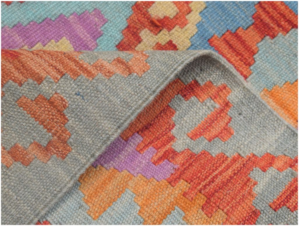 A handmade Afghan Maimana kilim runner featuring a geometric pattern in orange, purple, and blue.