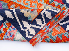 A folded Afghan Maimana Kilim runner featuring vibrant geometric patterns in wool.
