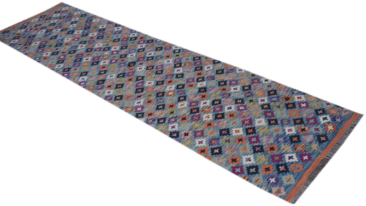 A handmade Afghan Maimana wool runner rug featuring a colorful geometric pattern.