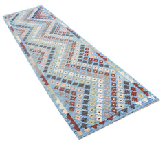 A handmade Afghan Maimana runner rug featuring a vibrant geometric pattern in blue and multi-colors.