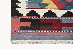 A close-up of an Afghan Maimana Kilim runner featuring geometric patterns in red, blue, and yellow.
