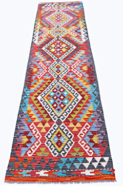 A handmade Afghan Maimana wool runner rug featuring a vibrant geometric pattern in a flatweave.