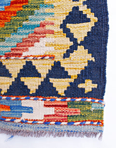 A handmade Afghan Maimana kilim runner featuring geometric patterns in vibrant wool colors.