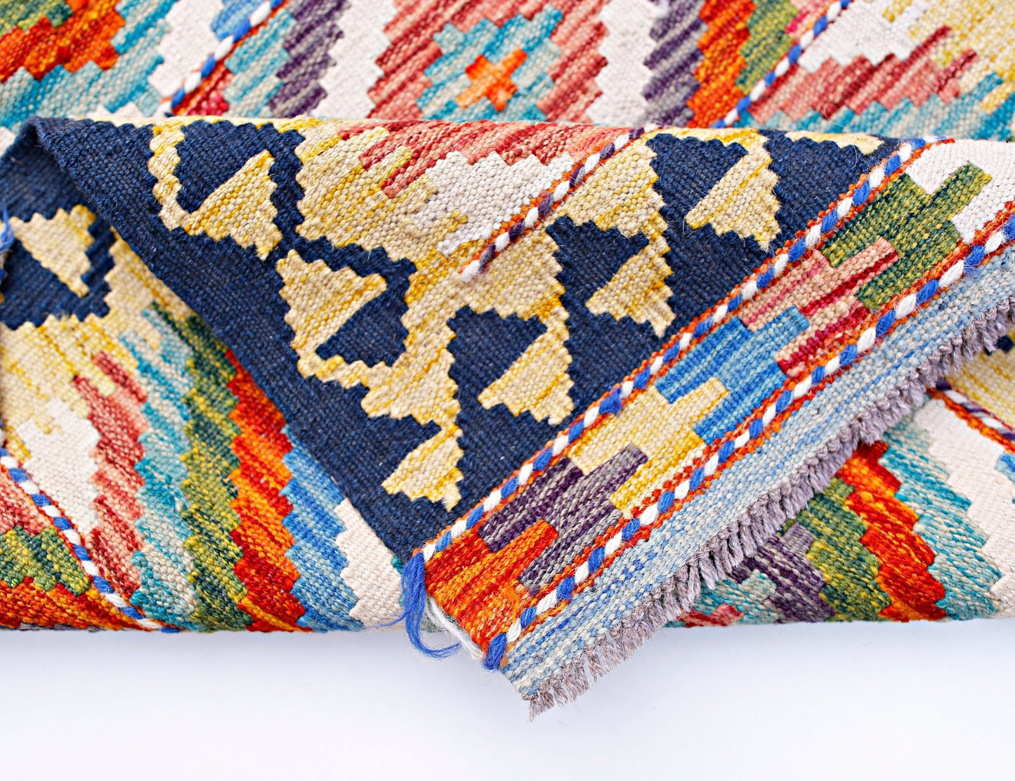 A folded Afghan Maimana kilim runner featuring vibrant geometric patterns in wool.
