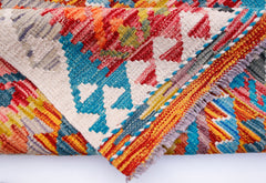 A folded Afghan Maimana kilim runner featuring vibrant geometric patterns in wool.