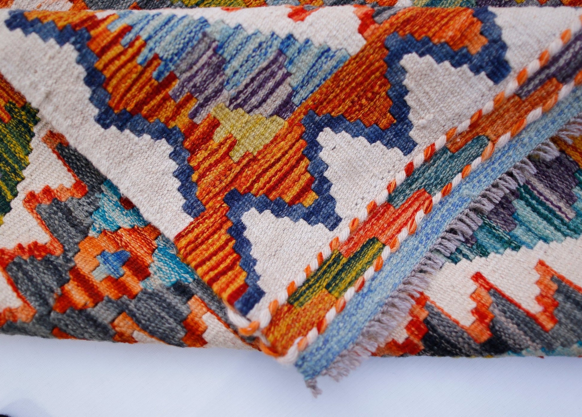 A handwoven Afghan Maimana kilim runner featuring a vibrant geometric pattern in wool.