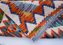 A handwoven Afghan Maimana kilim runner featuring a vibrant geometric pattern in wool.