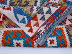 A folded Afghan Maimana Kilim runner featuring a vibrant geometric pattern in wool.