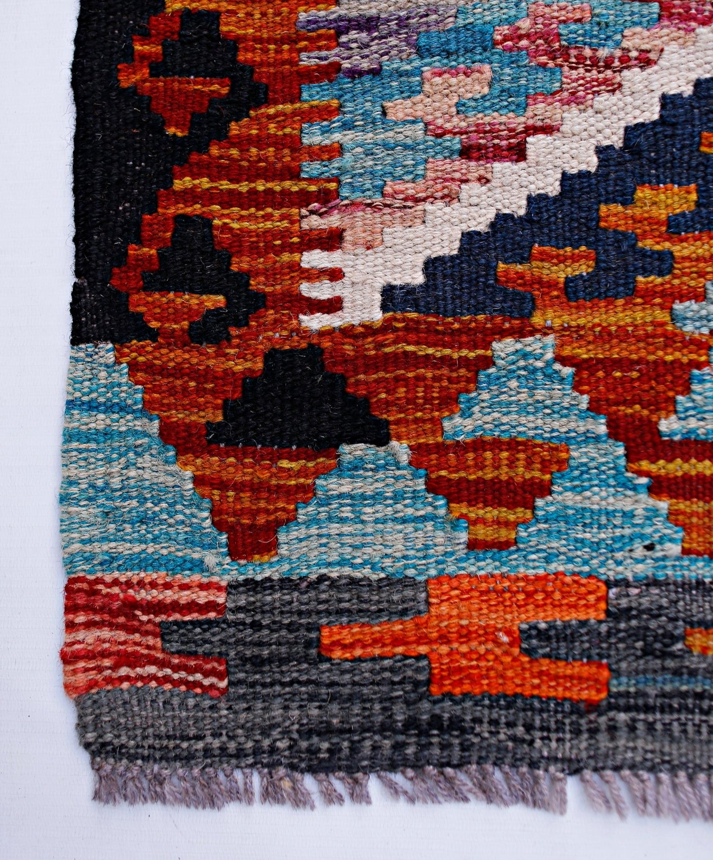 Handwoven Afghan Maimana wool runner featuring a vibrant geometric pattern in multi-colored tones.