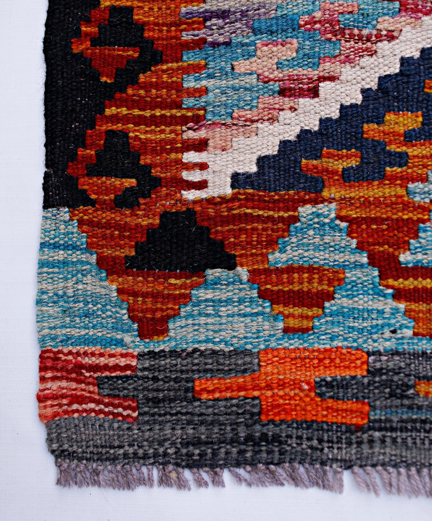 Handwoven Afghan Maimana wool runner featuring a vibrant geometric pattern in multi-colored tones.
