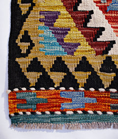 Handwoven Afghan Maimana kilim runner featuring geometric patterns in vibrant wool colors.