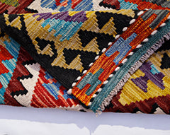 A folded Afghan Maimana kilim runner featuring vibrant geometric patterns in wool.