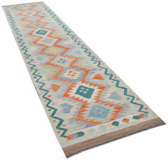 A handmade Afghan Maimana wool runner rug featuring a geometric pattern in orange, blue, and cream.
