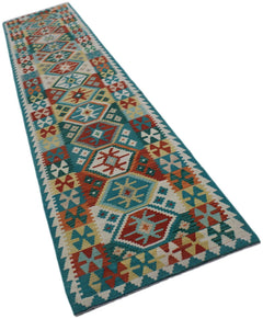A handmade Afghan Maimana wool runner rug featuring a colorful geometric pattern on a teal border.