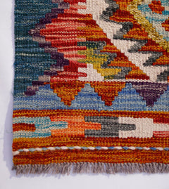 A handwoven Afghan Maimana wool runner featuring vibrant geometric patterns and a fringed edge.