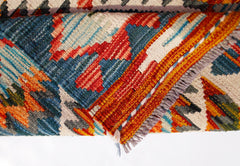 A folded Afghan Maimana kilim runner featuring vibrant geometric patterns in wool.