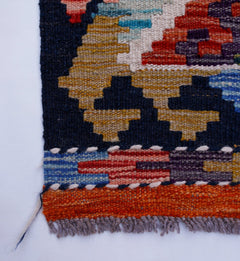 A close-up of a handwoven Afghan Maimana wool kilim runner featuring geometric patterns.