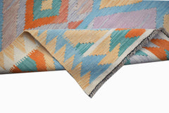 A handmade Afghan Maimana kilim runner featuring a geometric pattern in orange, blue, and cream.