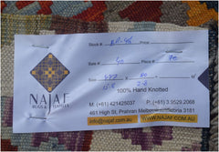 An Afghan Maimana Kilim runner featuring a colorful geometric pattern and a product tag.
