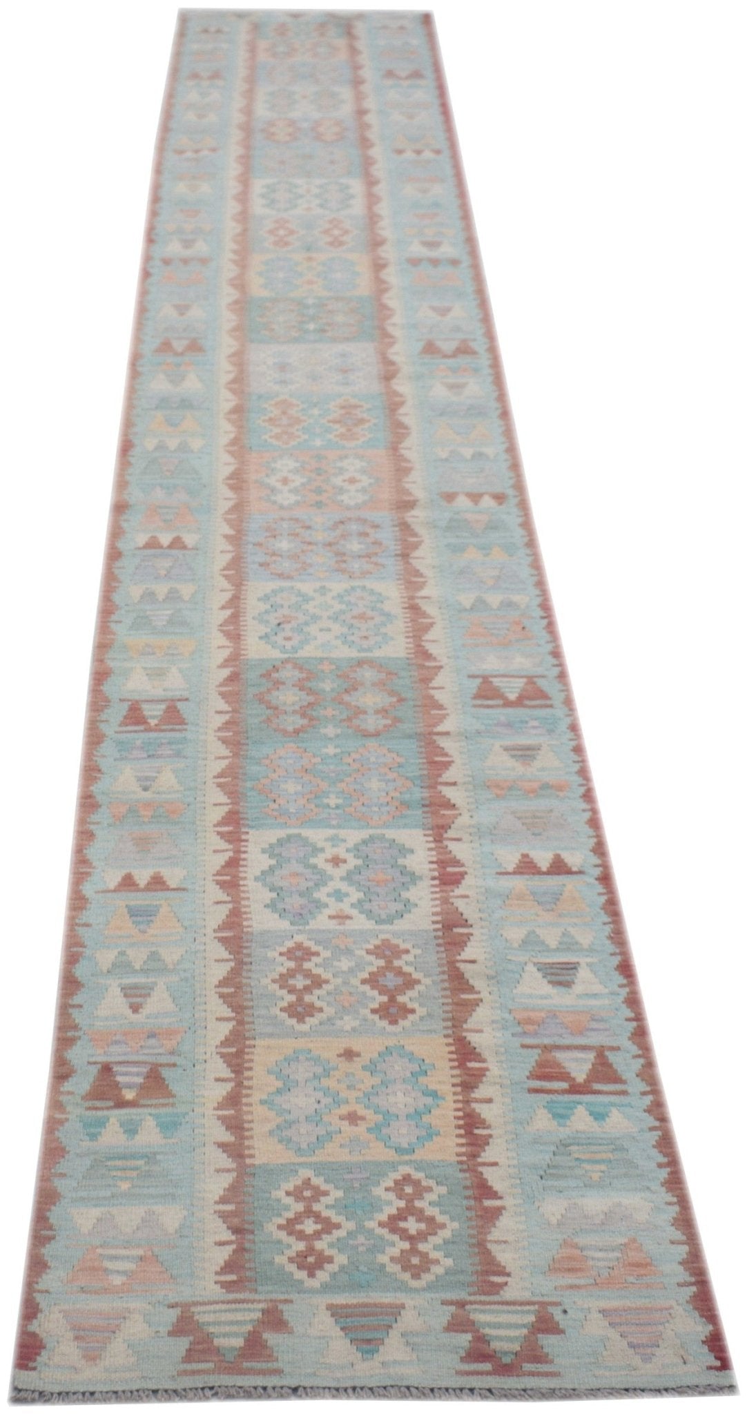 A handmade Afghan Maimana wool runner rug featuring a geometric pattern in soft blue and pink tones.