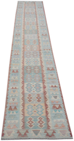 A handmade Afghan Maimana wool runner rug featuring a geometric pattern in soft blue and pink tones.
