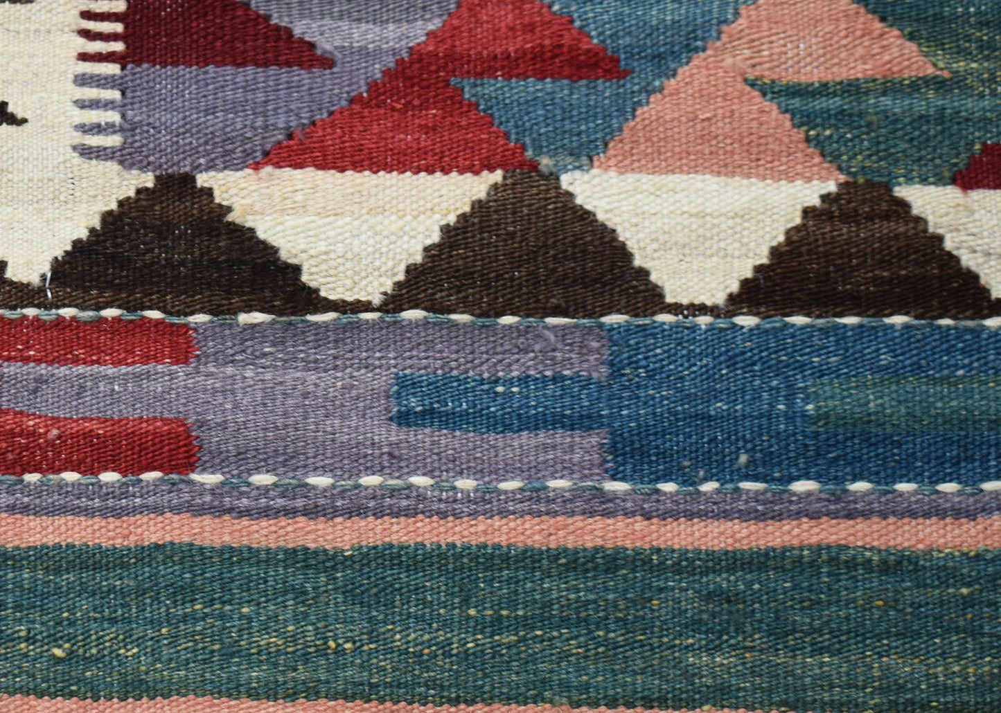 A close-up of a handwoven Afghan Maimana kilim runner featuring geometric patterns in wool.