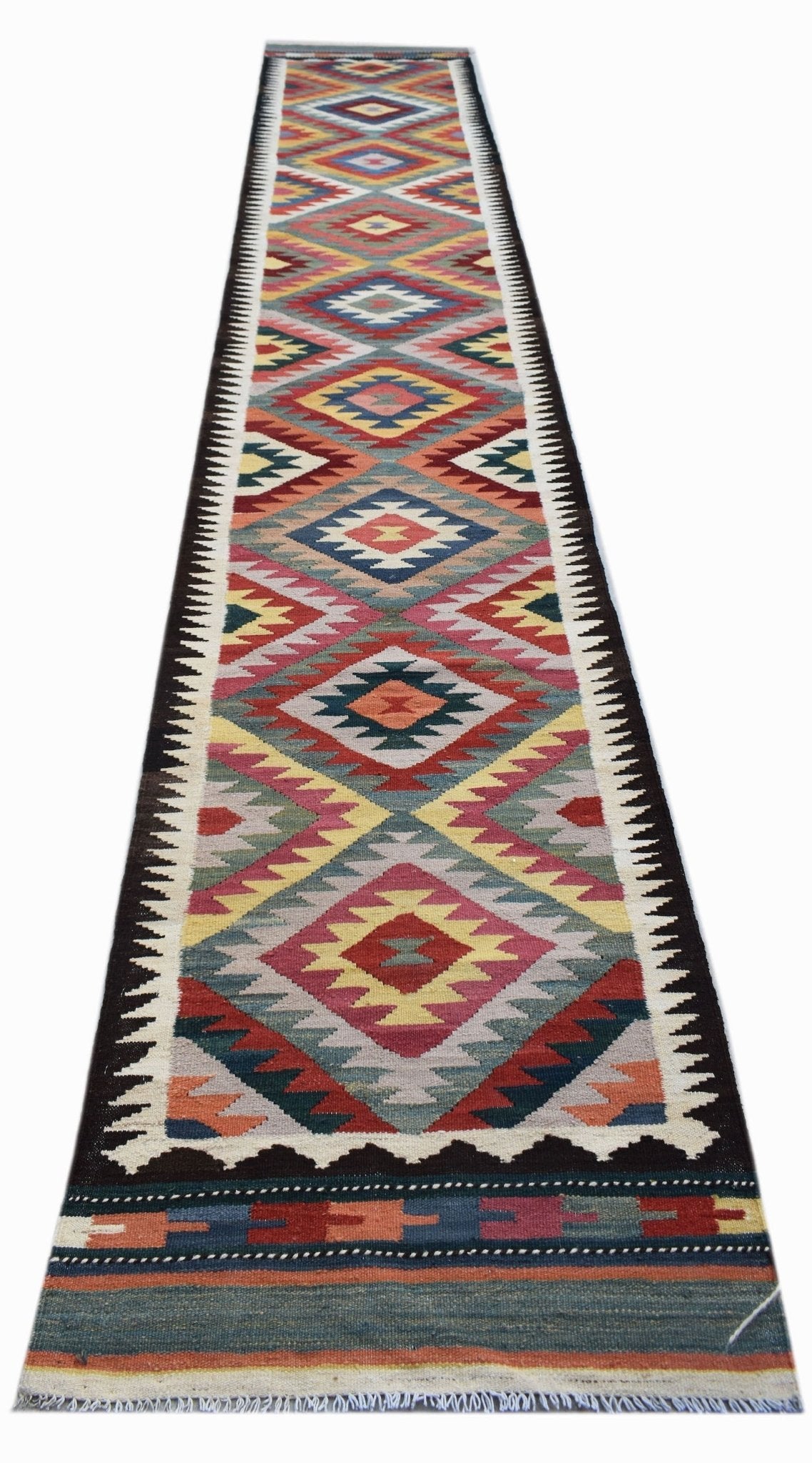 A long, handmade Afghan Maimana wool runner rug featuring a colorful geometric diamond pattern.
