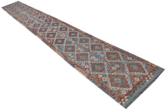 A long, handmade Afghan Maimana wool runner rug featuring a geometric diamond pattern in blue and red.