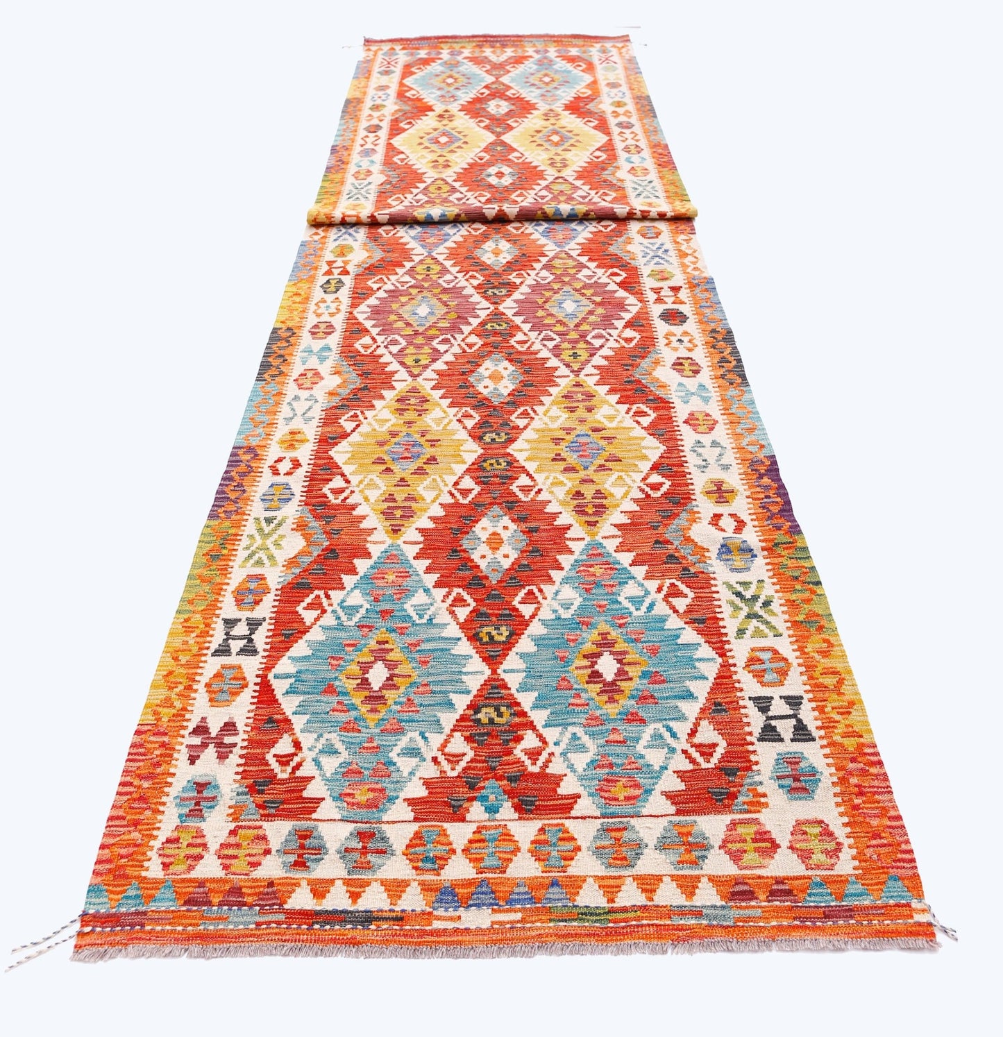 A long, handmade Afghan Maimana wool runner featuring vibrant geometric diamond patterns.
