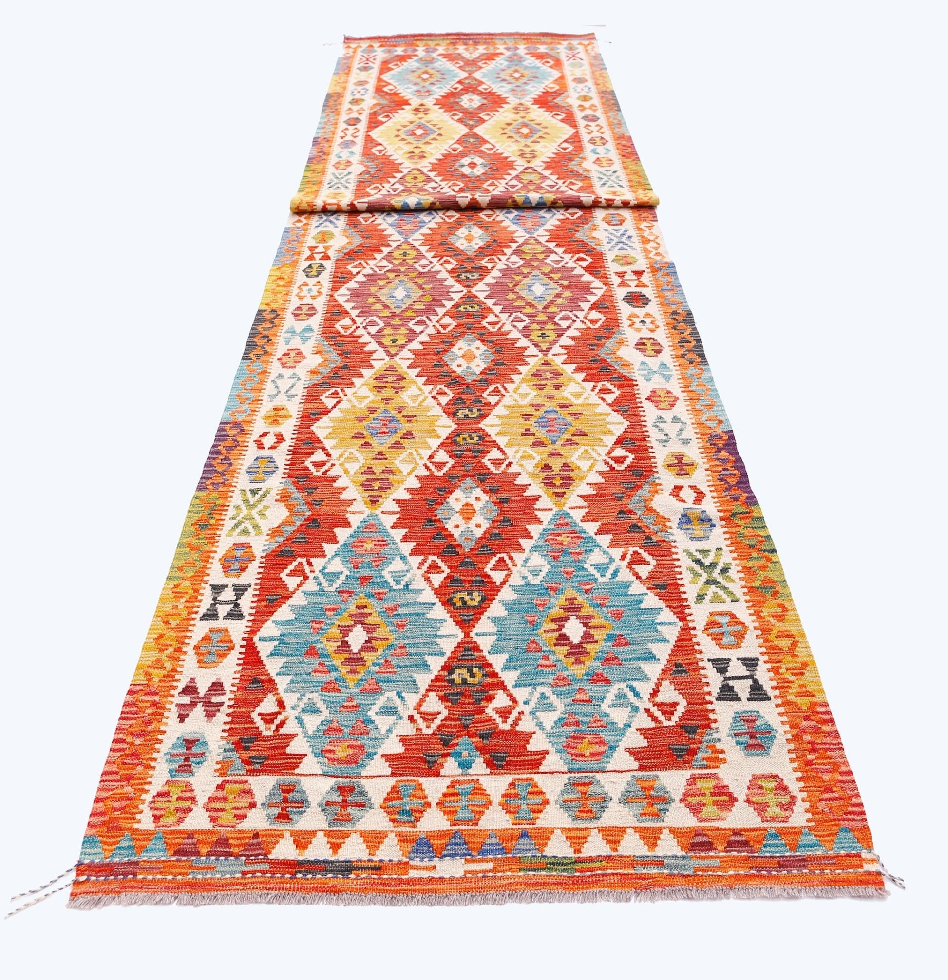 A long, handmade Afghan Maimana wool runner featuring vibrant geometric diamond patterns.