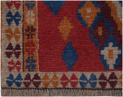 Handmade Afghan Pashm rug featuring a geometric tribal pattern in deep red, blue, and brown tones.