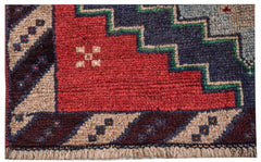 A handmade Afghan Pashm rug featuring a geometric pattern in deep red, blue, and ivory wool.