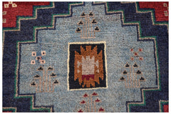 Handmade Afghan Pashm rug featuring a central geometric motif in blue, red, and brown wool.