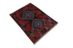 A handmade Afghan Pashm rug featuring geometric diamond patterns in red, blue, and brown tones.