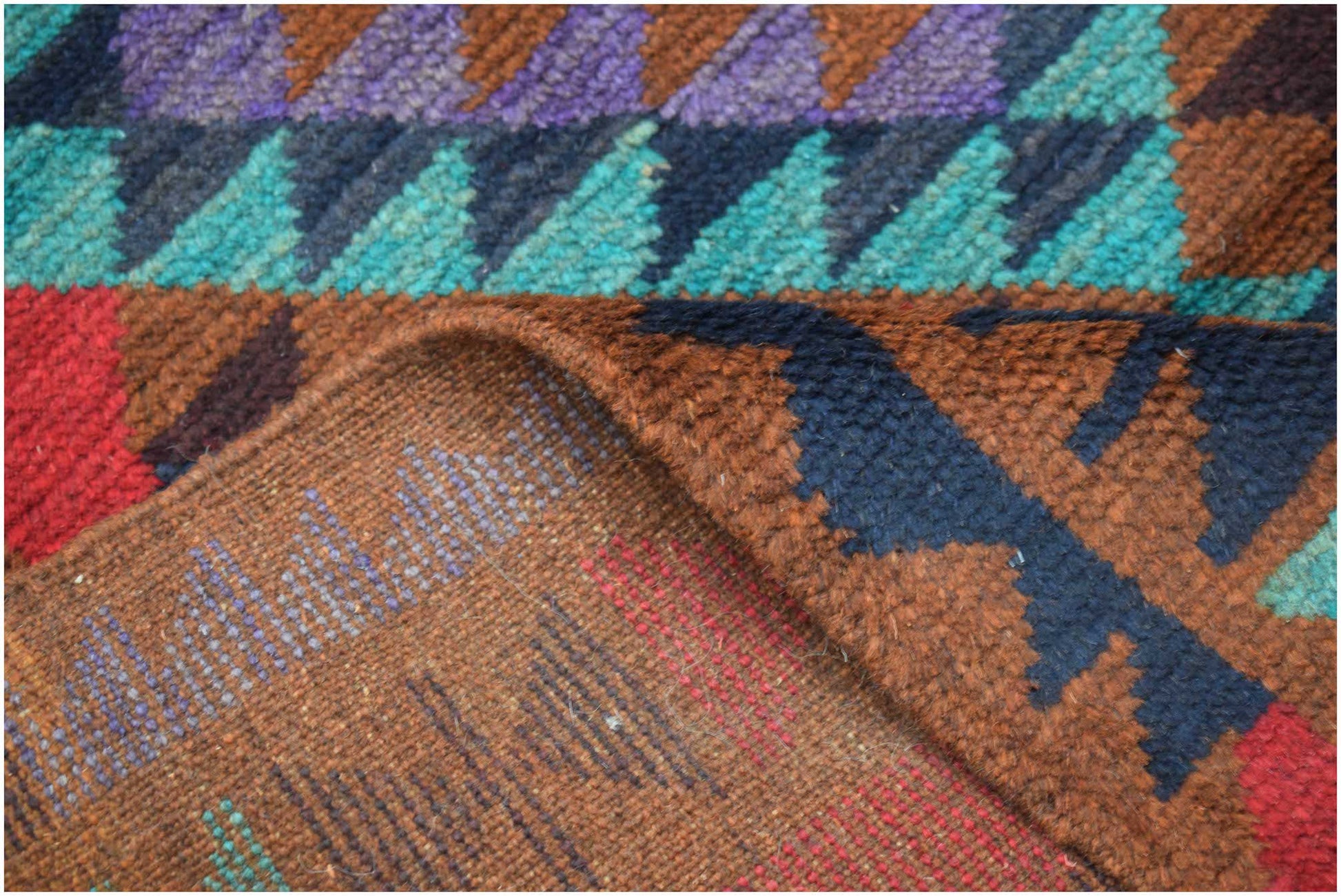A handmade Afghan Pashm rug featuring a geometric pattern in shades of red, blue, and brown.