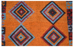 Handmade Afghan wool rug featuring a vibrant orange field with repeating geometric diamond motifs.