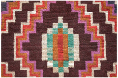 A handmade Afghan Pashm rug featuring a geometric diamond pattern in dark brown, red, and teal.