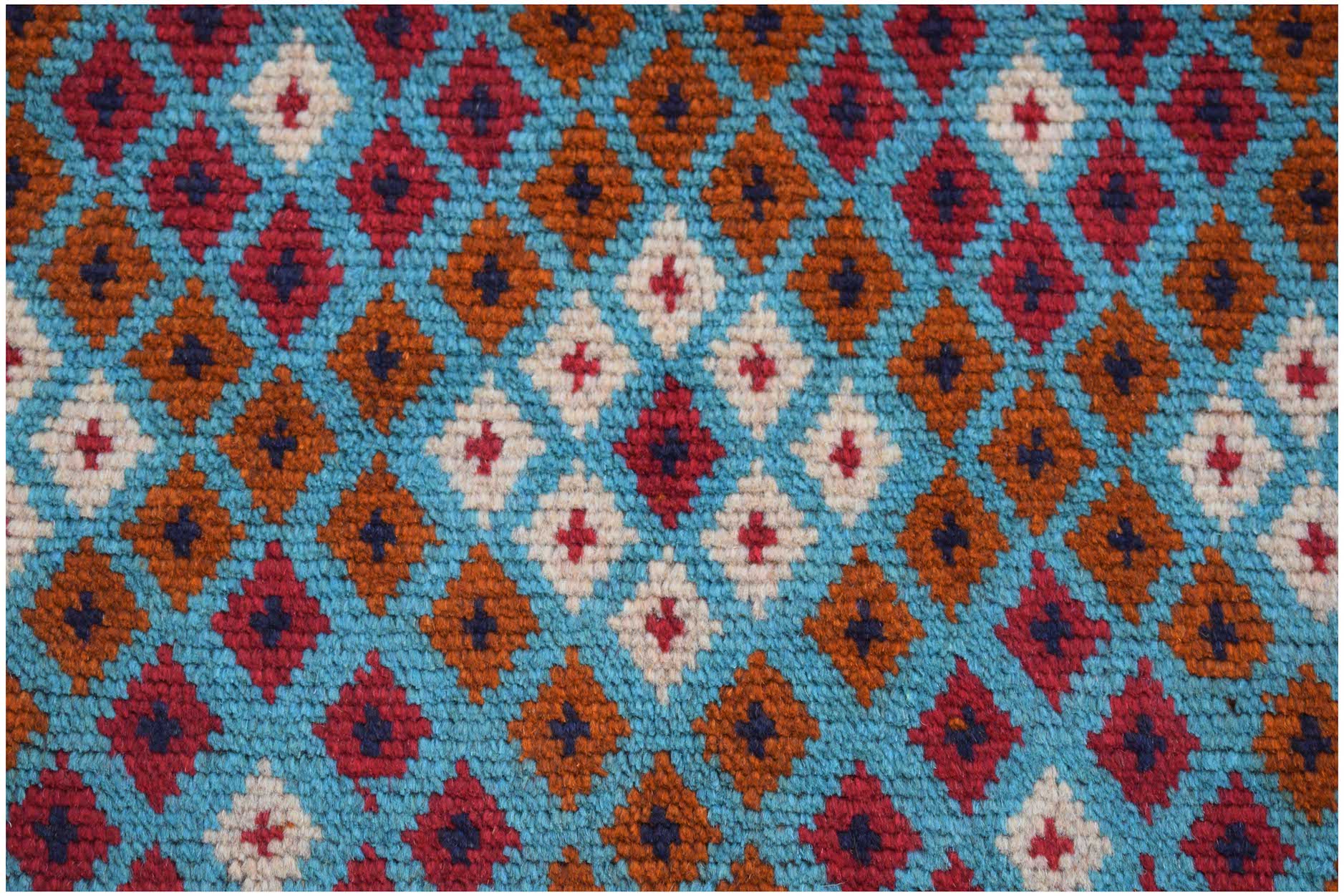 Handmade Afghan Pashm rug featuring a geometric diamond pattern in red, brown, blue, and ivory.